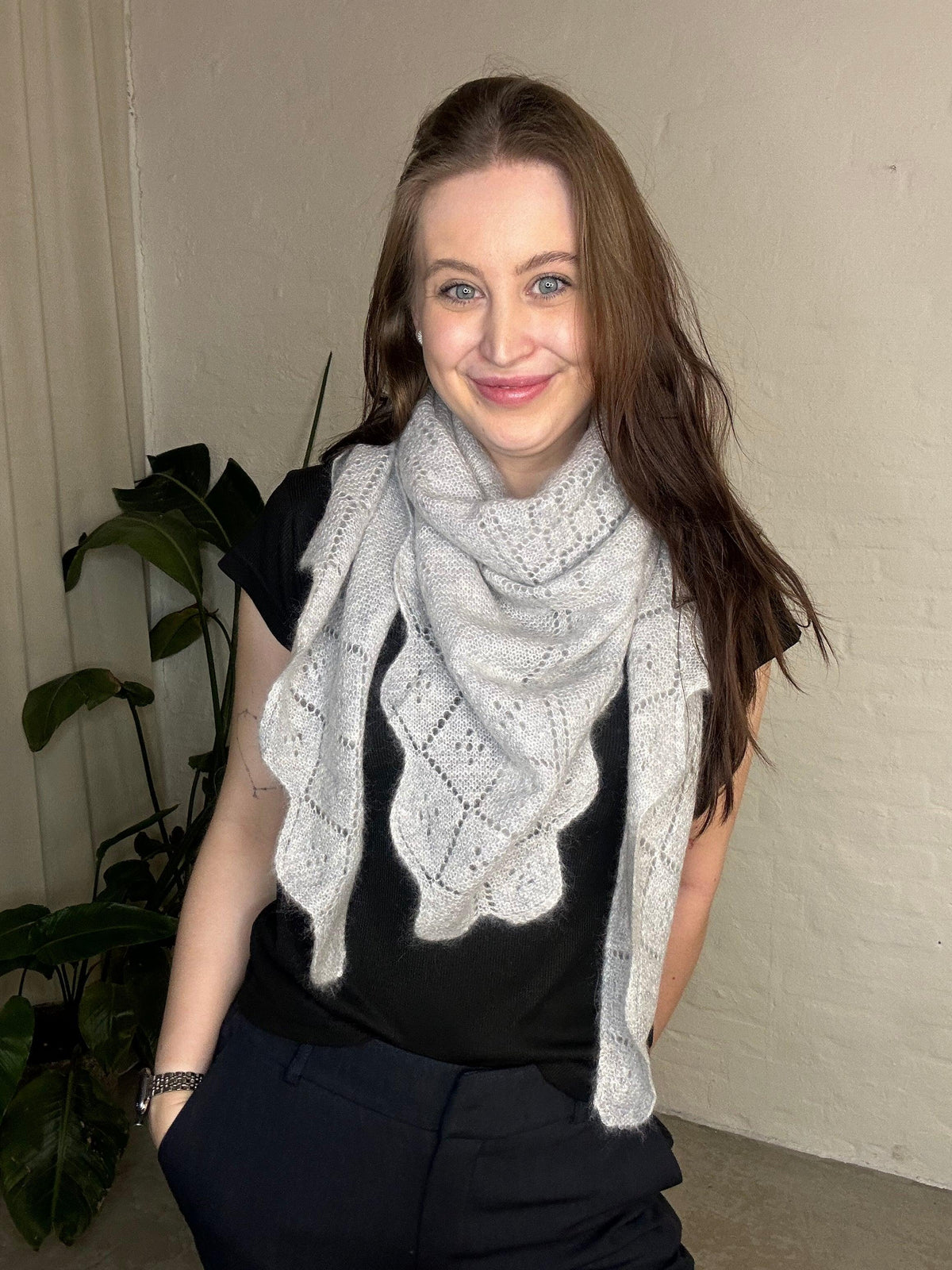 Kvinde iført gråt Andcopenhagen Basics cashmere tørklæde, Triangle trinity stor, foran neutral baggrund.