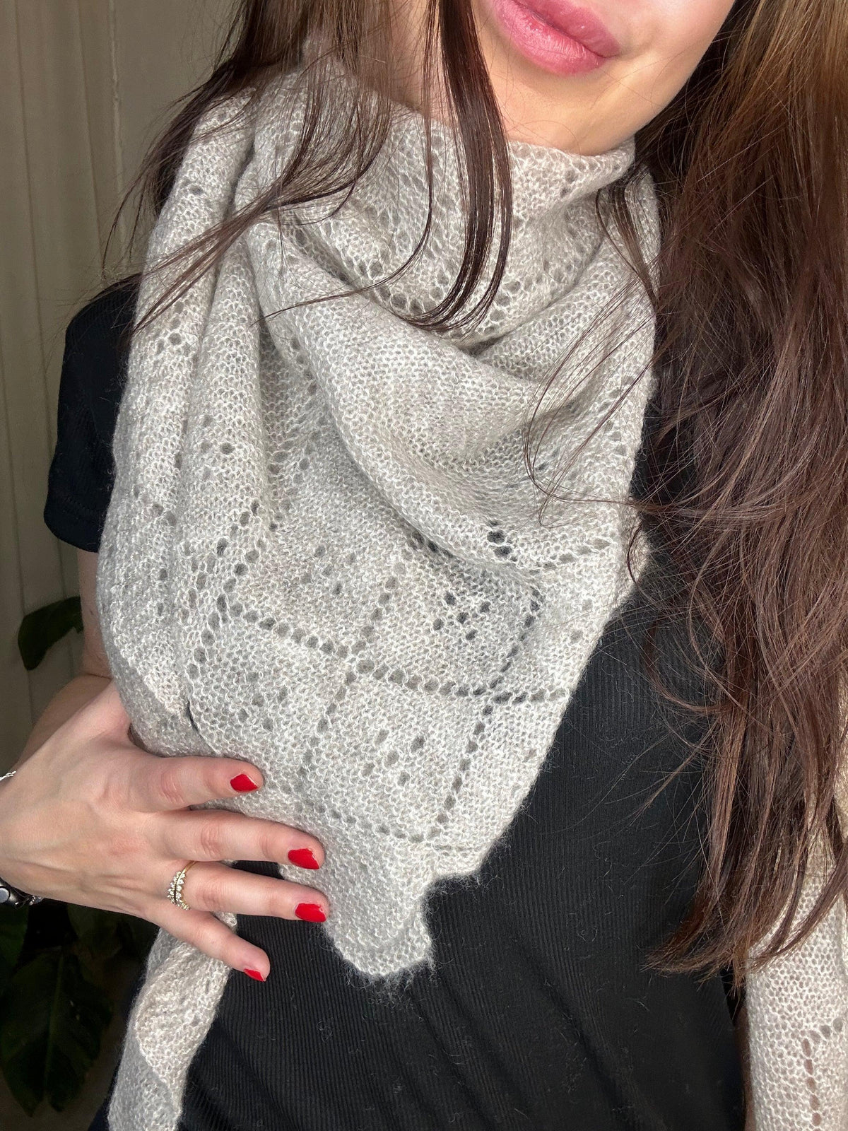 Kvinde iført Andcopenhagen Basics Cashmeretørklæde i lys beige, trekantet design, 100% cashmere.