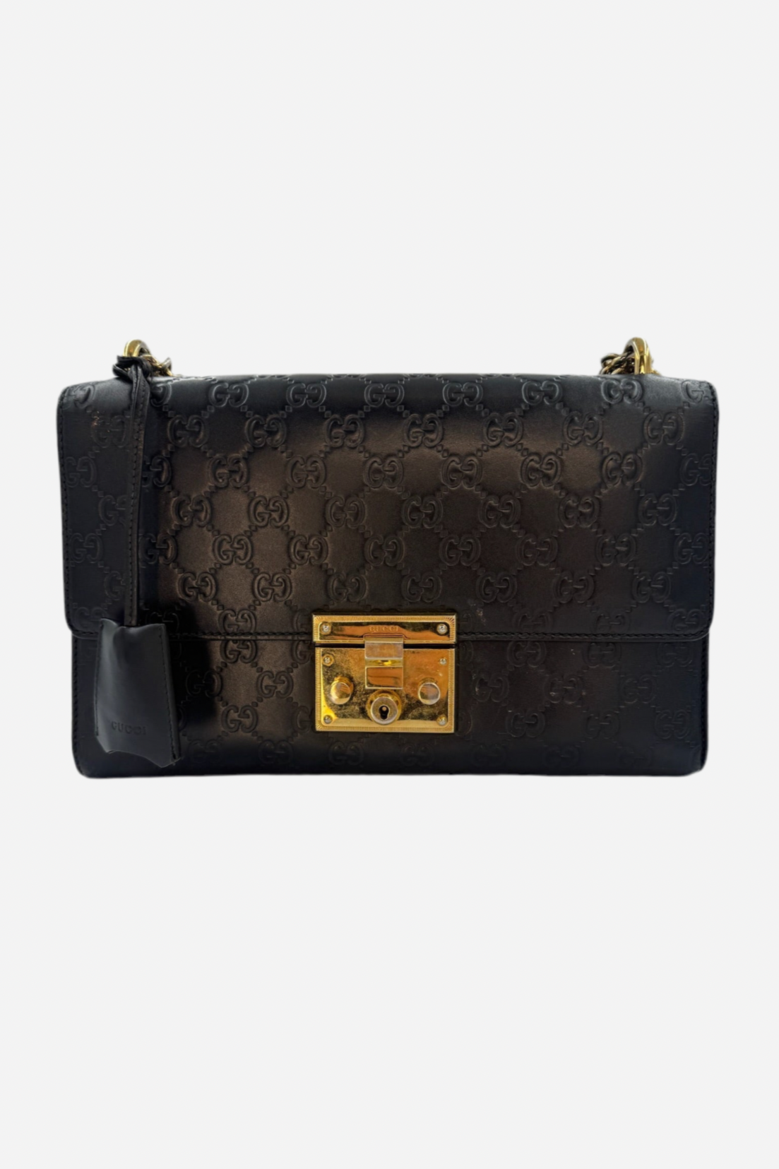 Sort Gucci-håndtaske med Guccissima-mønster og gylden lås. Sort lædertag hænger fra håndtaget.