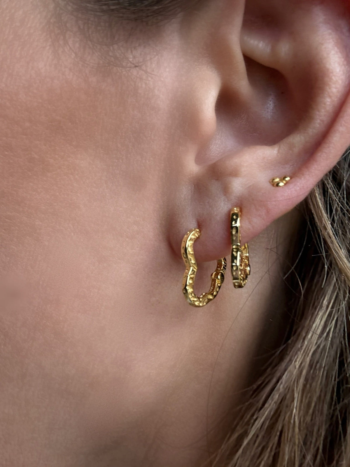Nærbillede af øre med Liza Heart Hoops øreringe i 18 karat forgyldt 925 sterlingsølv fra Andcopenhagen Jewelry.