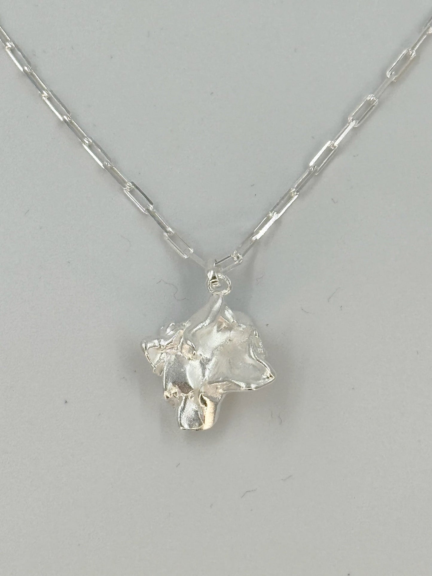 Sølvhalskæde med flade led og skulpturelt, organisk vedhæng.