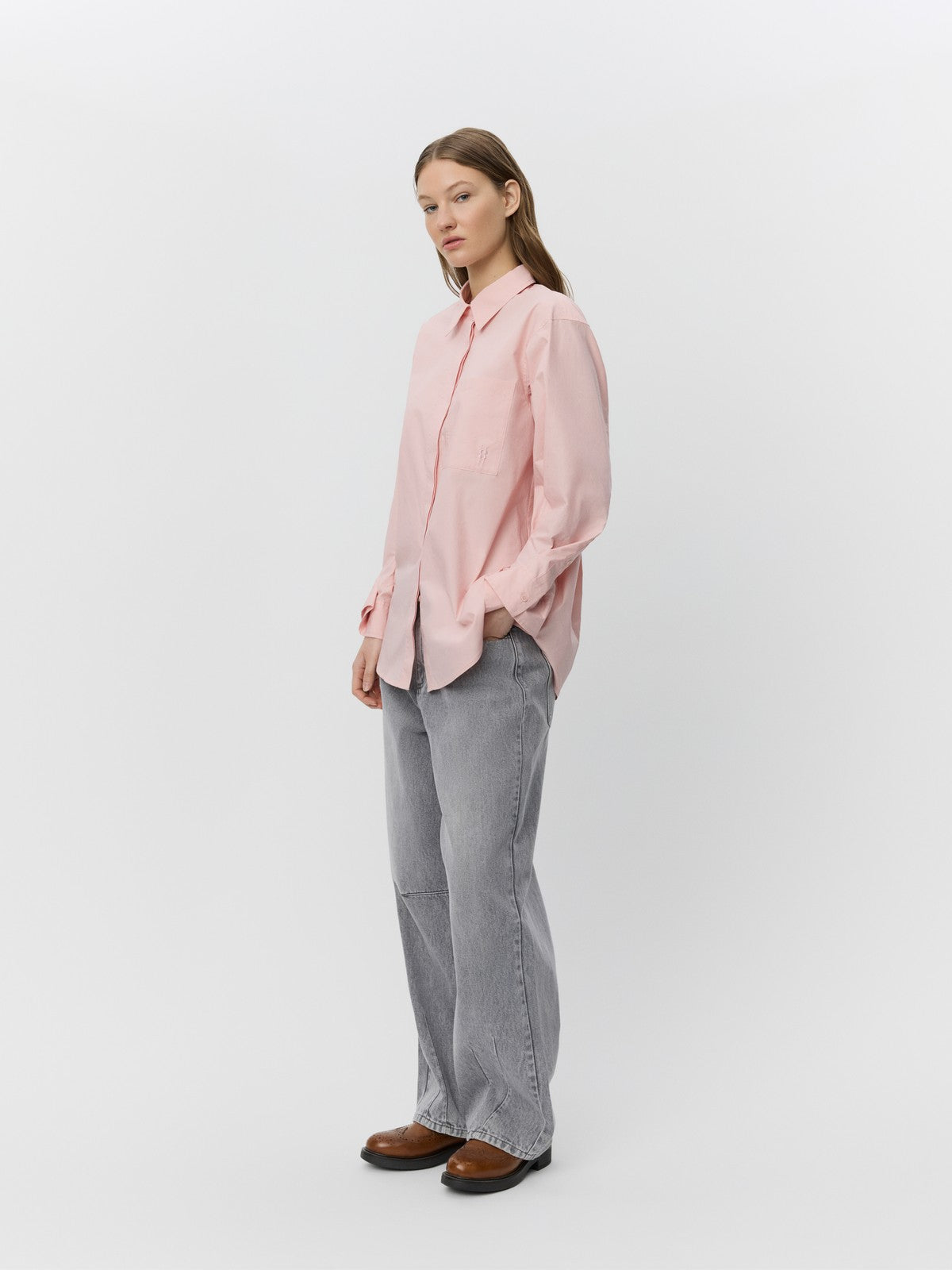 Lys pink skjorte med klassisk krave, brystlomme og rynkede manchetter, båret af person.
