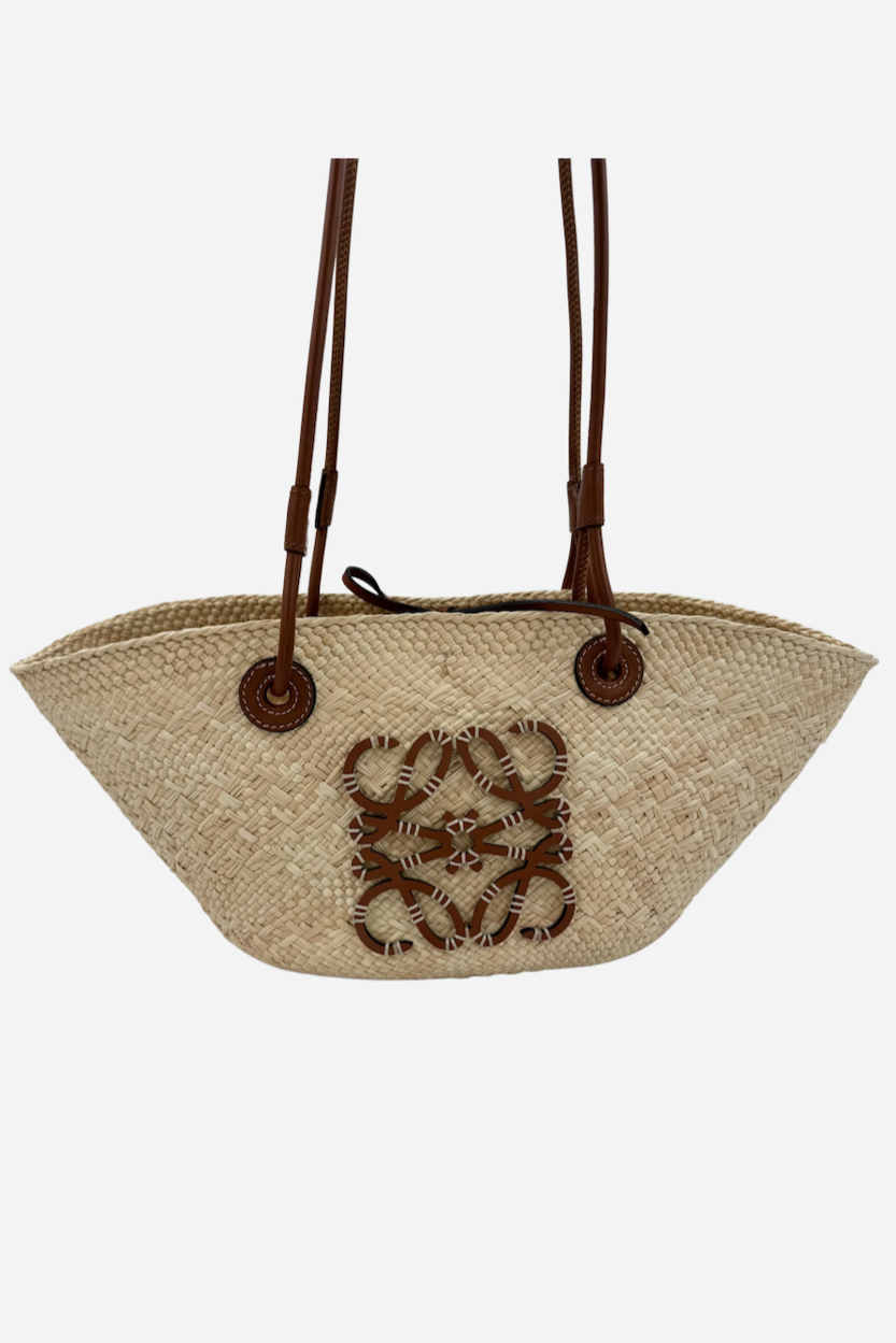 Vævet kurvetaske med trekantet form, naturlig fiber, læderstropper og dekorativt mønster.