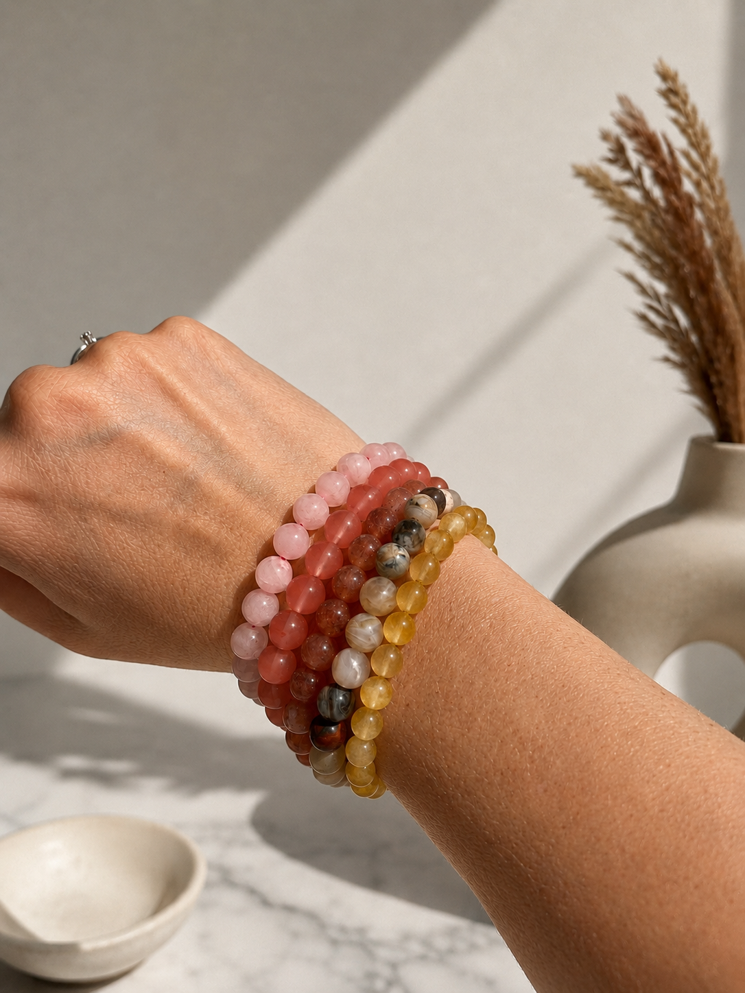 Gult Tora armbånd fra Andcopenhagen Jewelry vist på hånd sammen med andre farvede perlearmbånd.