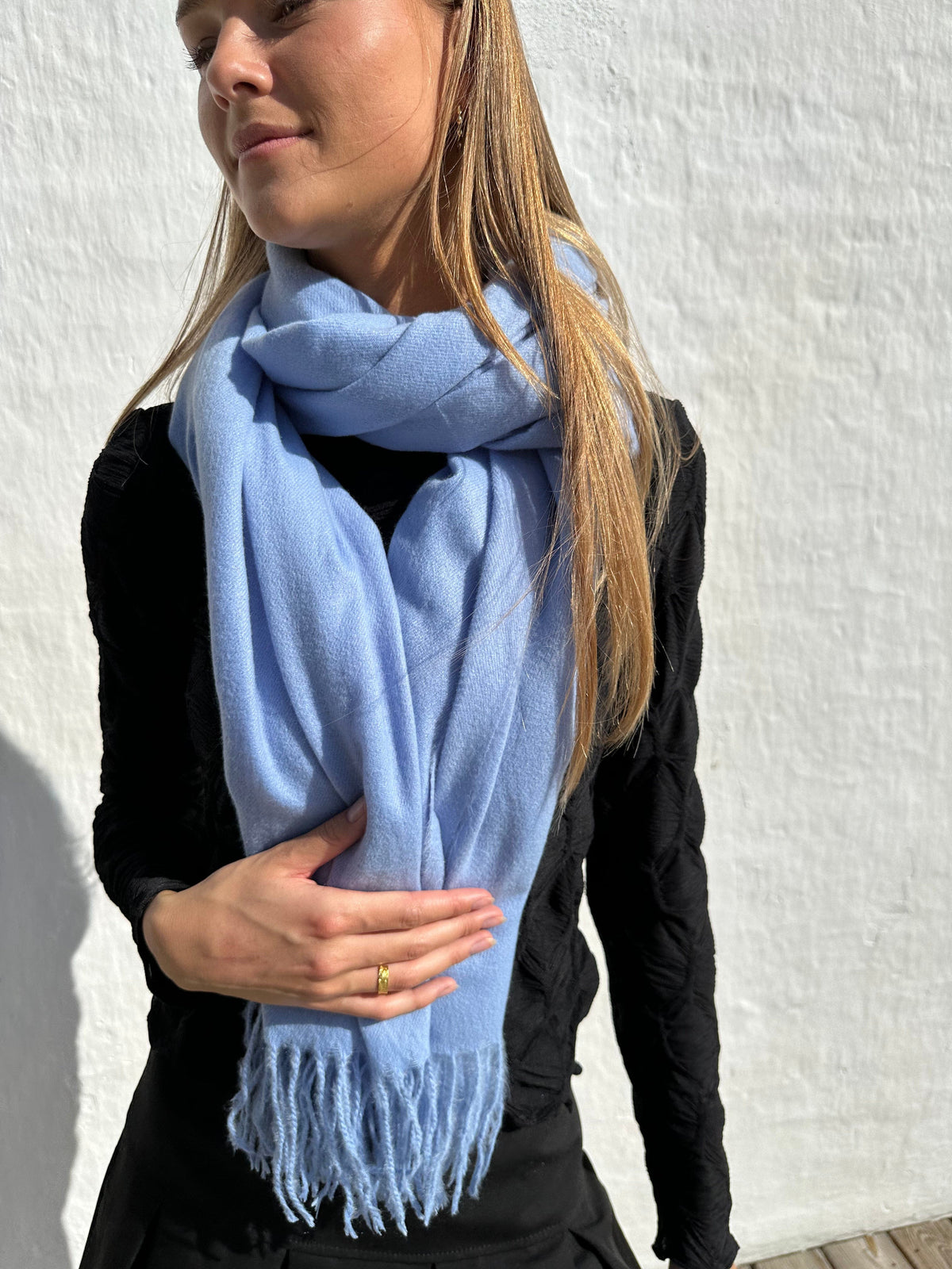 Kvinde iført Andcopenhagen Basics Cashmere Tørklæde i lyseblå, model Yana, mod hvid baggrund.