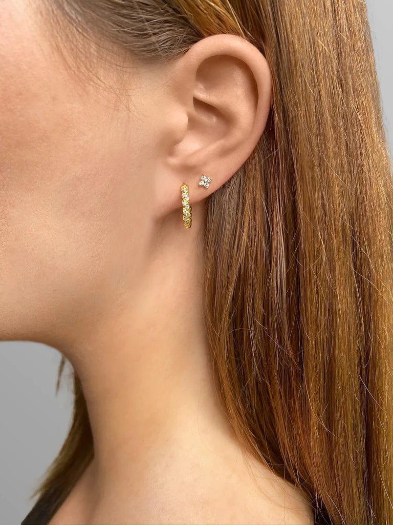 En kvindes øre med Andcopenhagen øreringe studs i 18 karat guldbelagt sterlingsølv, Flower-model.