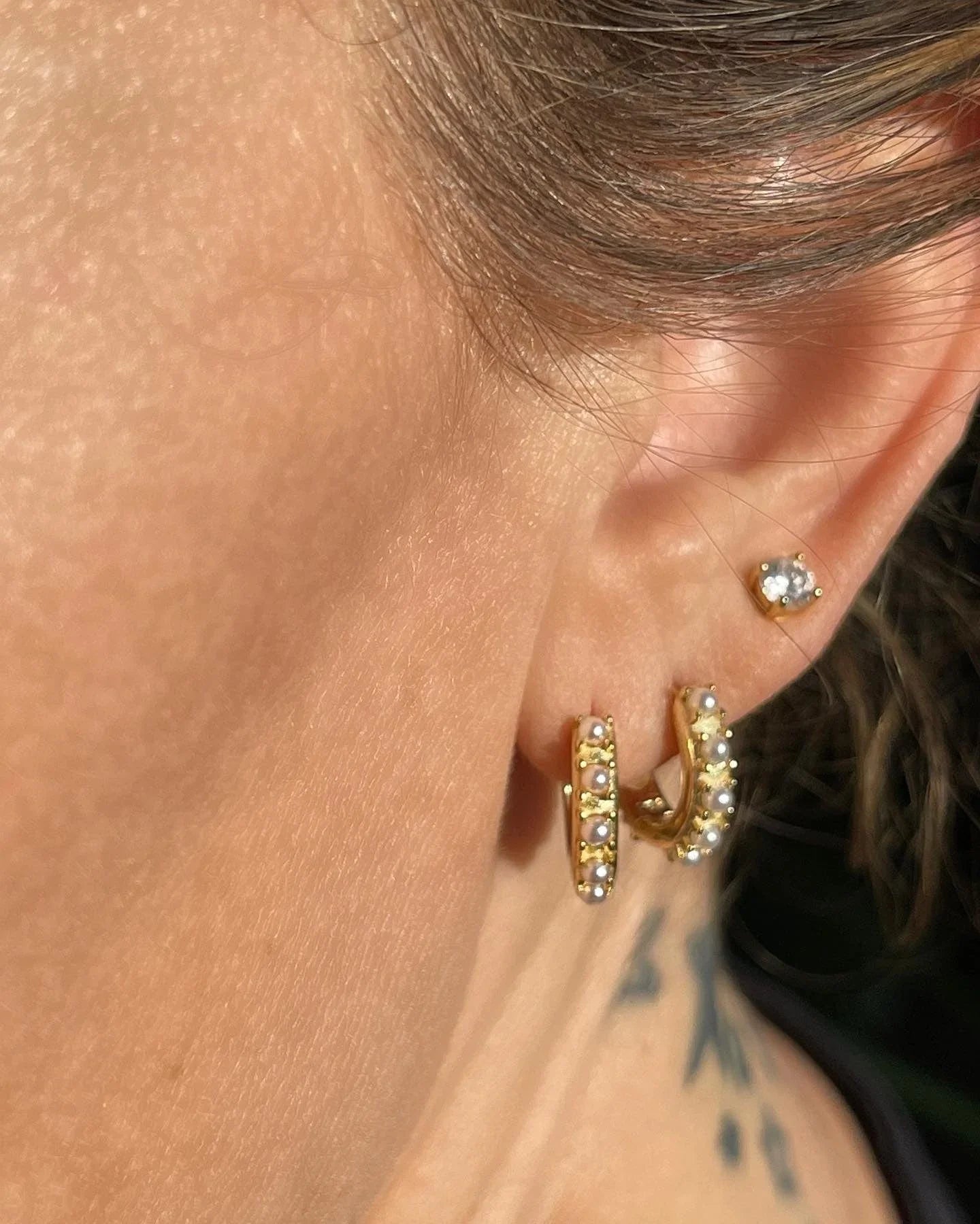 Kvinde bærer Andcopenhagen øreringe studs i 18 karat guldbelagt sølv med lille pop zirkon.