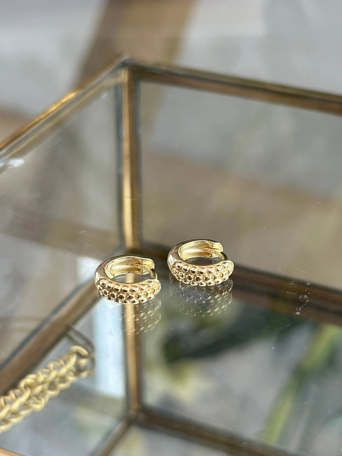 Chunky Dottie hoops fra Andcopenhagen i 18 karat guldbelagt 925 sterlingsølv på glasdisplay.