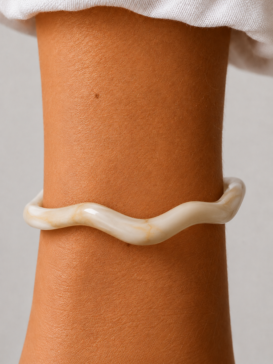 Hvid, bølget resinarmbånd fra Andcopenhagen Jewelry, bæres på håndled.