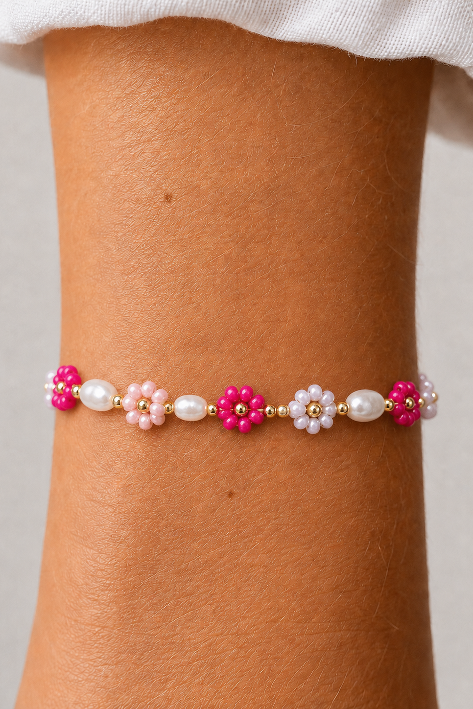 Perlearmbånd med fuchsia og lyserøde blomsterperler fra Andcopenhagen Jewelry på en arm.