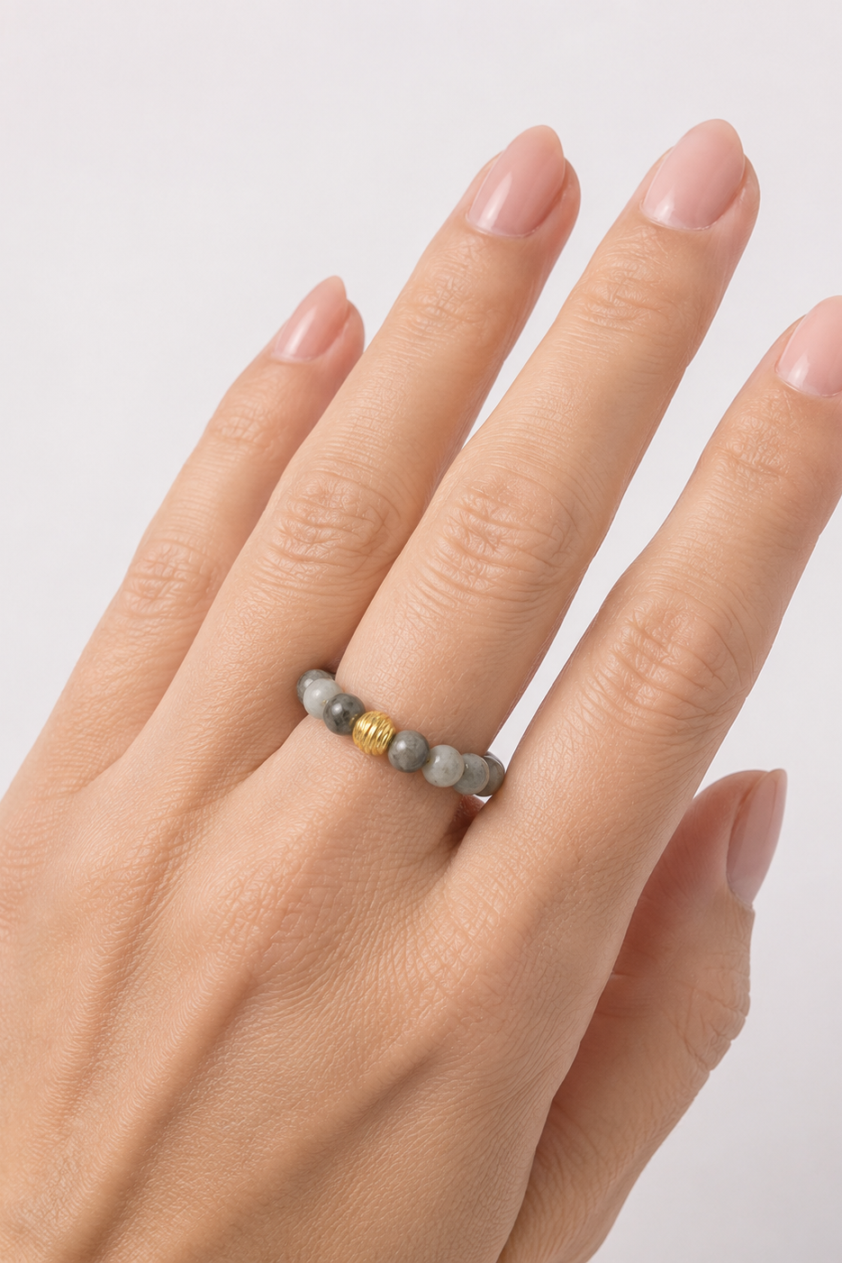 Hånd med Andcopenhagen Jaspis Sesam Mio-ring i grå sten og gulddetalje på finger.