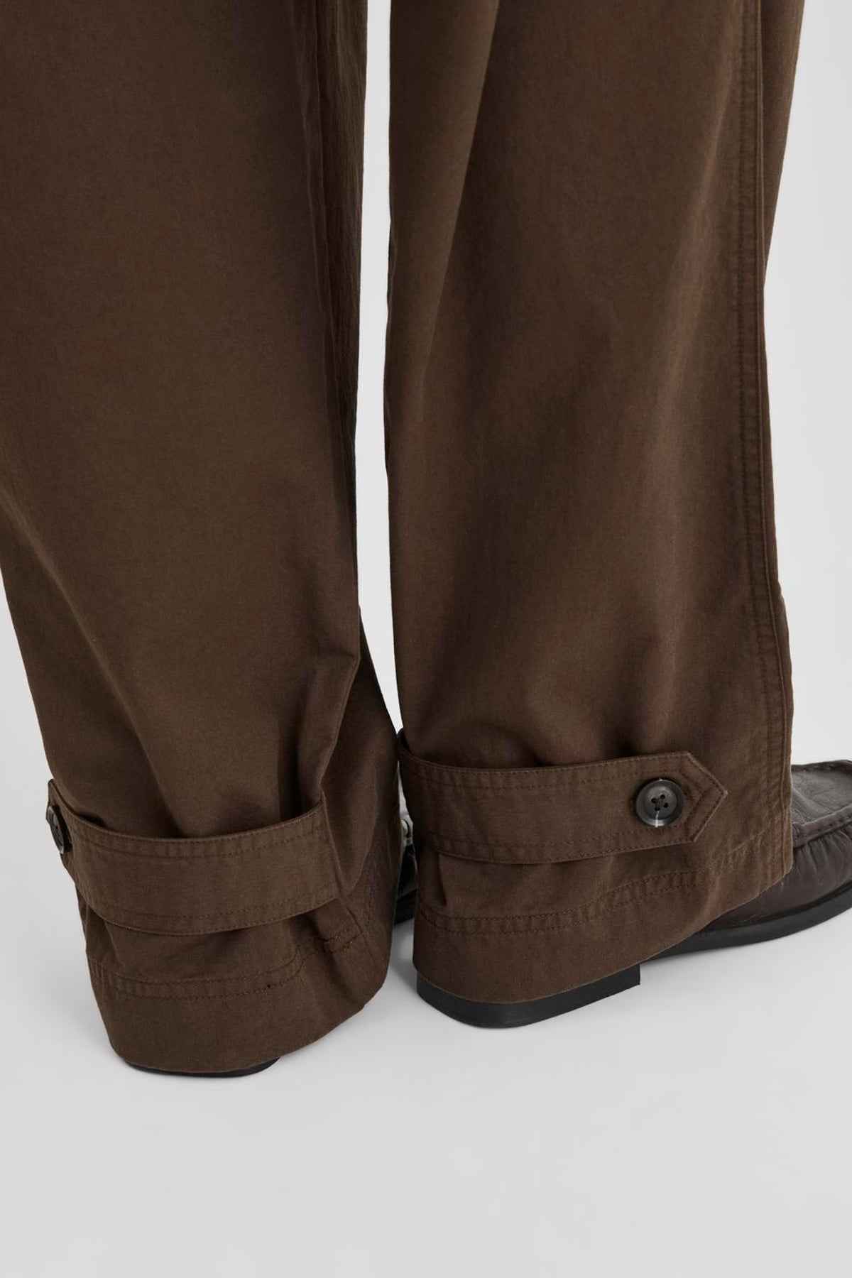 Vila ROUFIONA HW W/F F/L TROUSER in dark brown cotton fabric, close-up detail of the hem and buttoned strap.