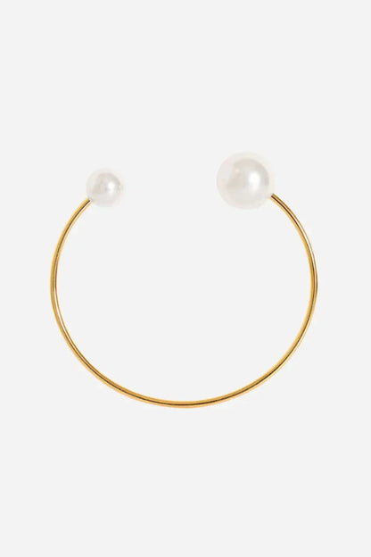 Minimalistisk bangle i guldbelagt stål med en hvid perle i hver ende.