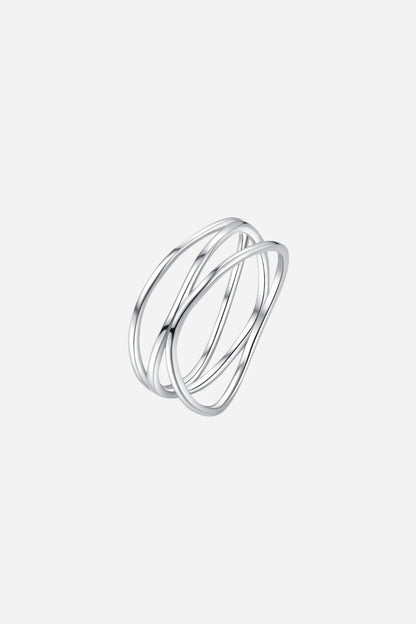 Sølvring med snoet design og overlappende tråde, skinnende på gennemsigtig overflade.