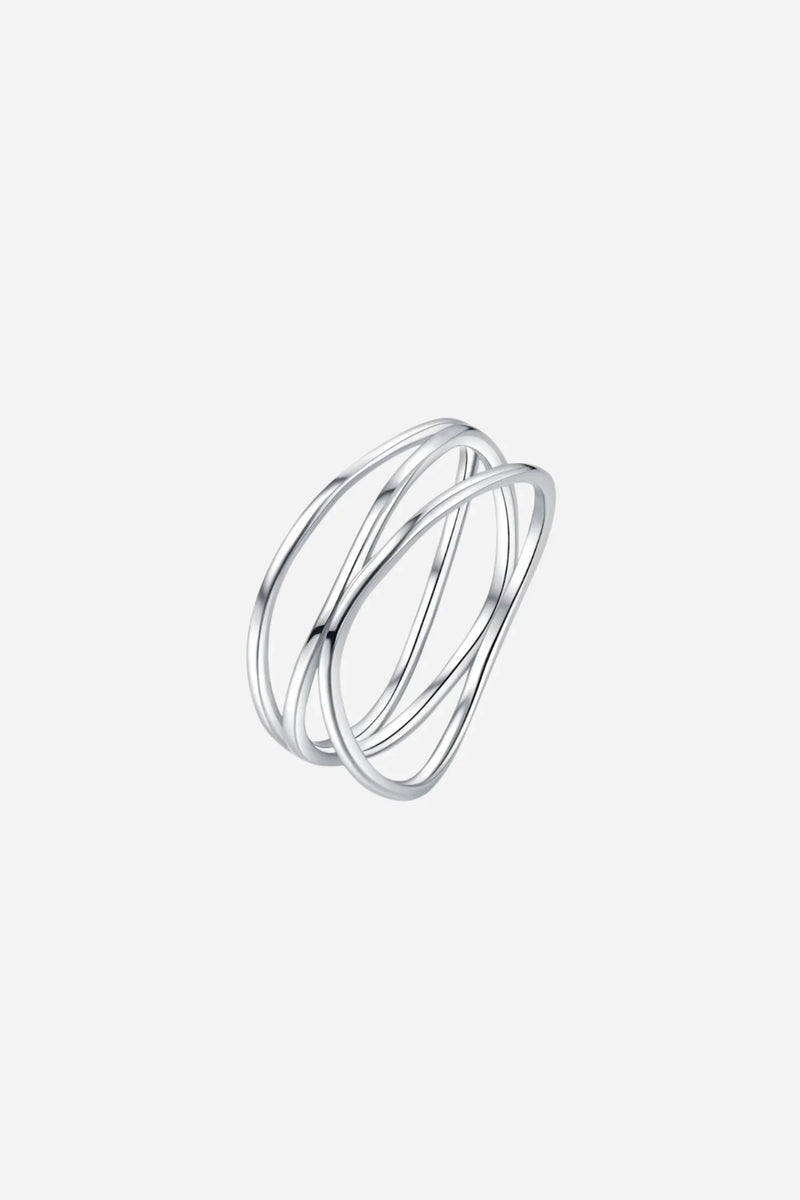 Sølvring med snoet design og overlappende tråde, skinnende på gennemsigtig overflade.