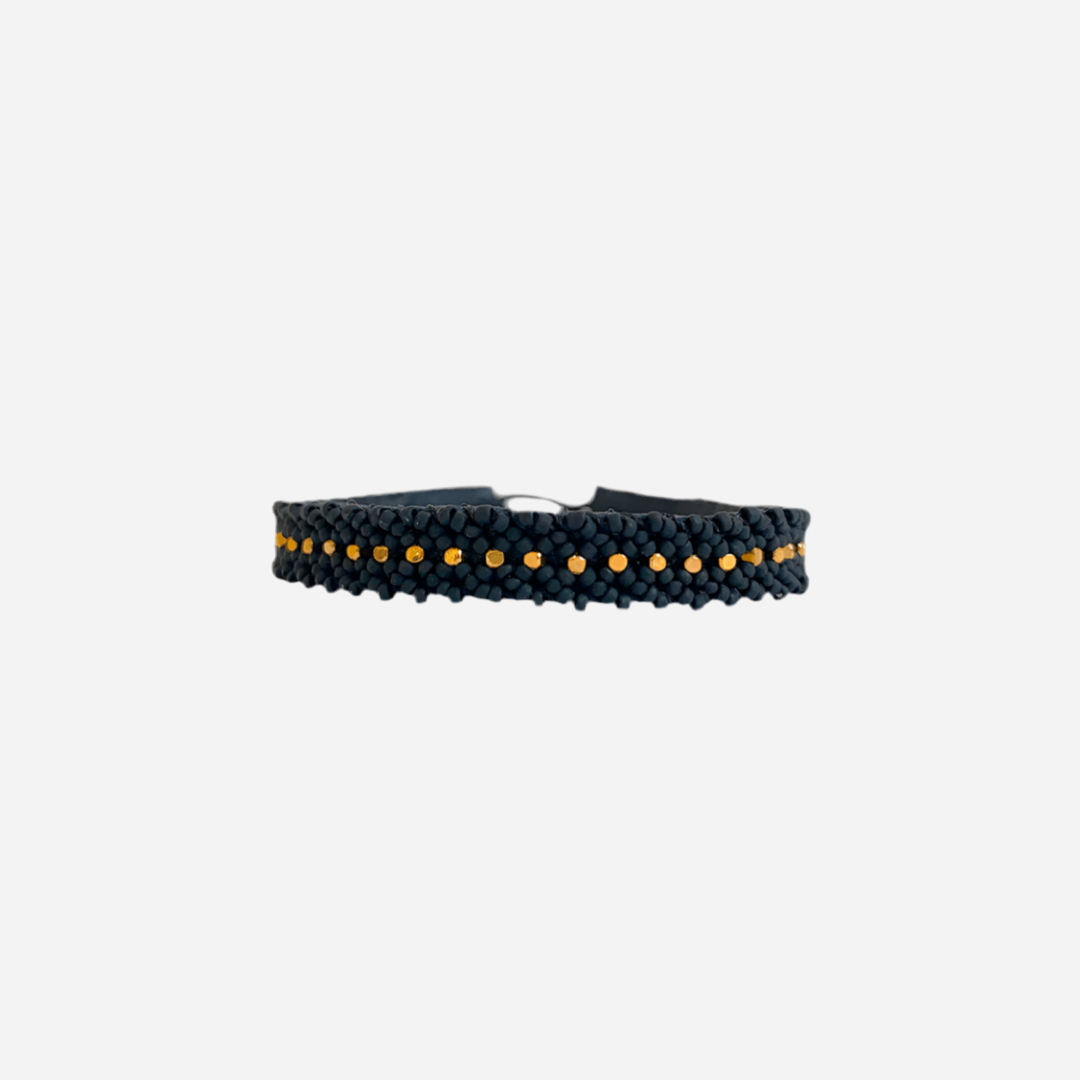 Sort flettet armbånd med små guldperler i midten, enkel og elegant stil.