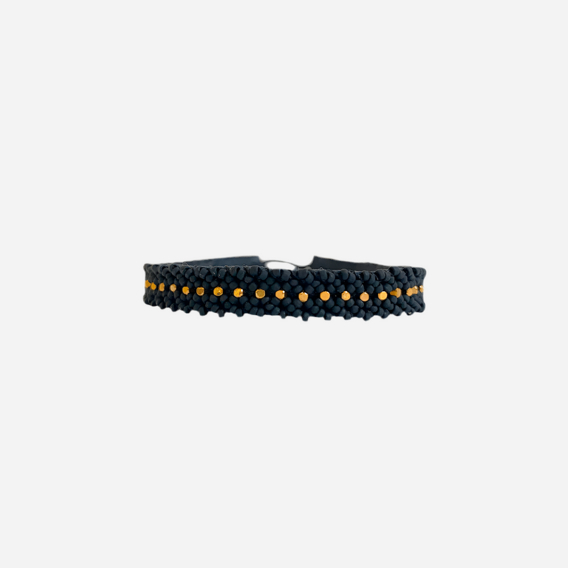 Sort flettet armbånd med små guldperler i midten, enkel og elegant stil.