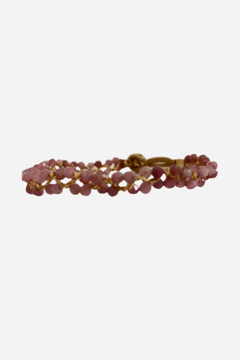 Håndlavet armbånd med lyserøde perler i et flettet mønster, bundet med gylden tråd.