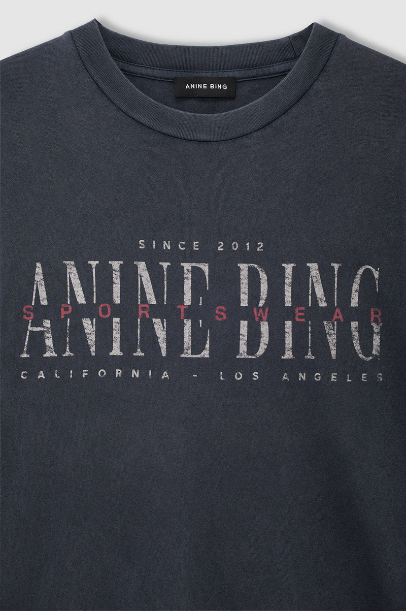 Cade Tee Sport Club fra Anine Bing er en cool og afslappet T-shirt, der kombinerer et sporty udtryk med brandets karakteristiske vintage-stil.