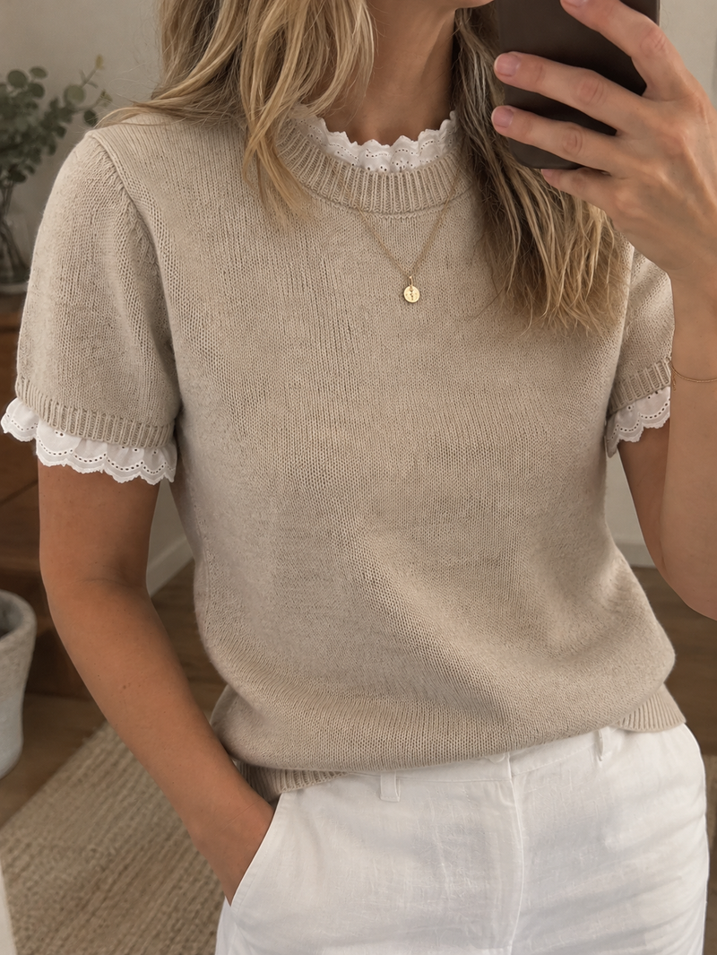 Nirvana er en feminin og stilfuld strikbluse, der kombinerer et klassisk design med romantiske detaljer