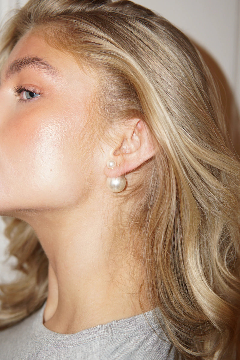 Kvinde med Sophie double pearl øreringe fra Andcopenhagen Jewelry, vist på øret.