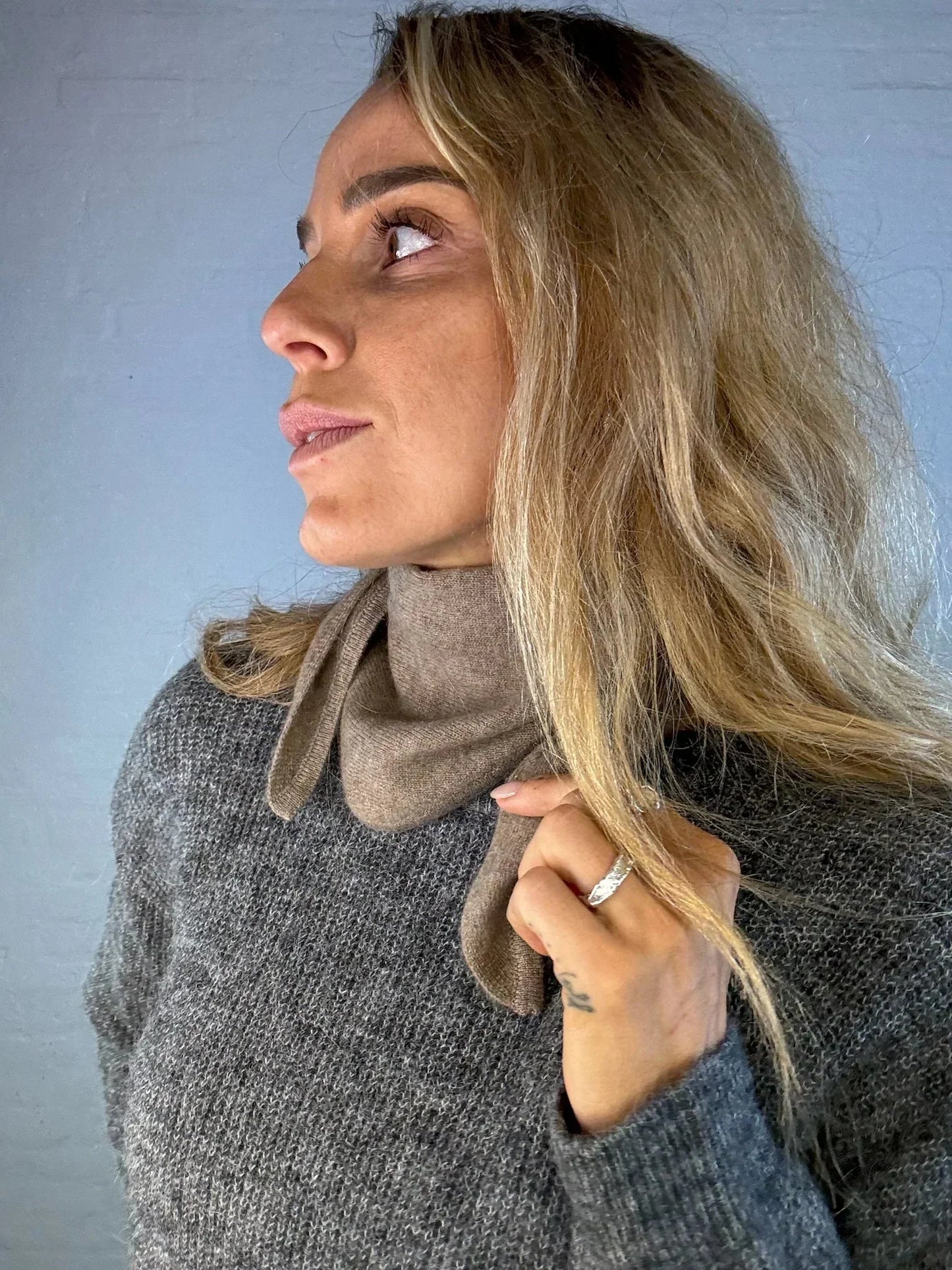 Model med mørkebrun cashmere mini tørklæde om halsen. Tørklædet er blødt og elegant.