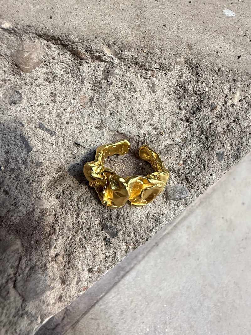 Andcopenhagen Arlinda ring i 18 karat guldbelagt 925 sterlingsølv vist på en rå betonflade.