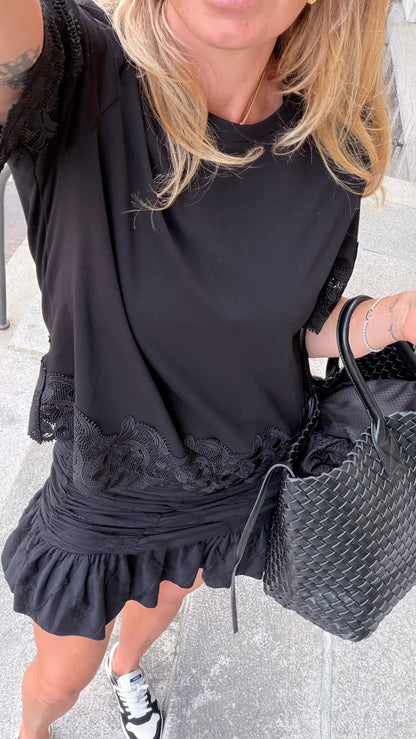 Kvinde med sort kjole holder Andcopenhagen Basics taske i sort vegansk læder fra Noella.