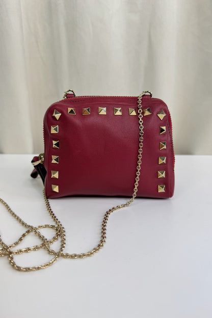 Rød Valentino taske med guldnitter og kæde. Enkel baggrund.