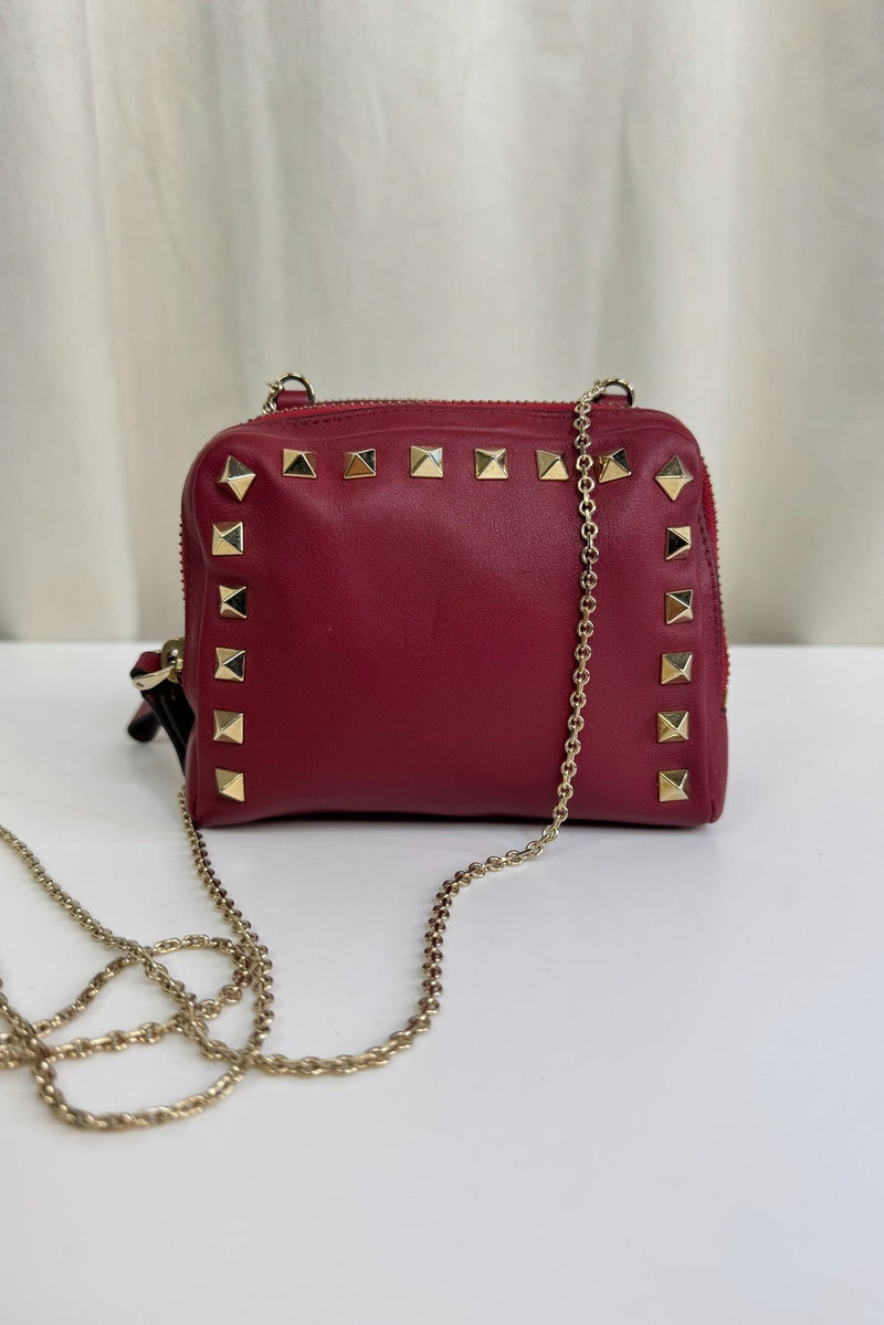 Rød Valentino taske med guldnitter og kæde. Enkel baggrund.