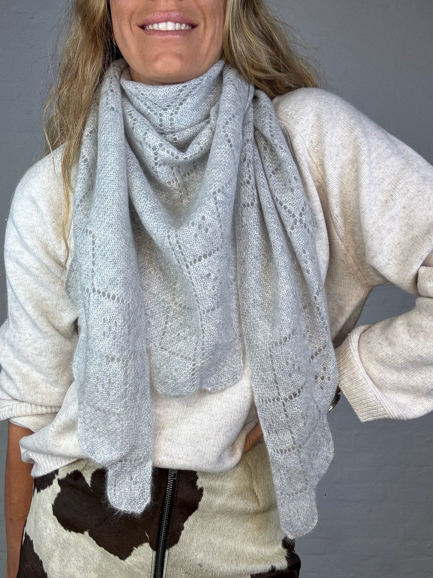 Gråt trekantet cashmere tørklæde med bladmønster, båret af person i lys trøje.