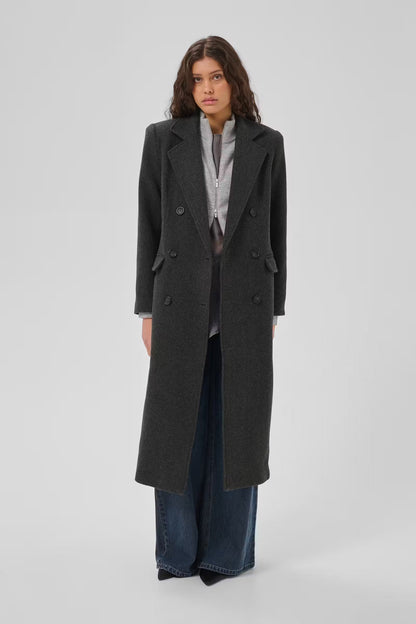 Frannie-frakken fra My Essential Wardrobe er en klassisk, lang frakke i den elegante farve Dark Grey Melange på mørkhåret kvinde