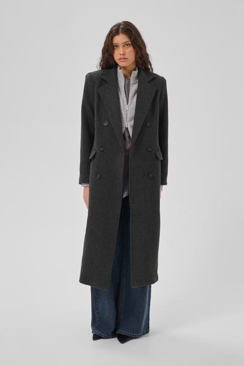 Frannie-frakken fra My Essential Wardrobe er en klassisk, lang frakke i den elegante farve Dark Grey Melange på mørkhåret kvinde