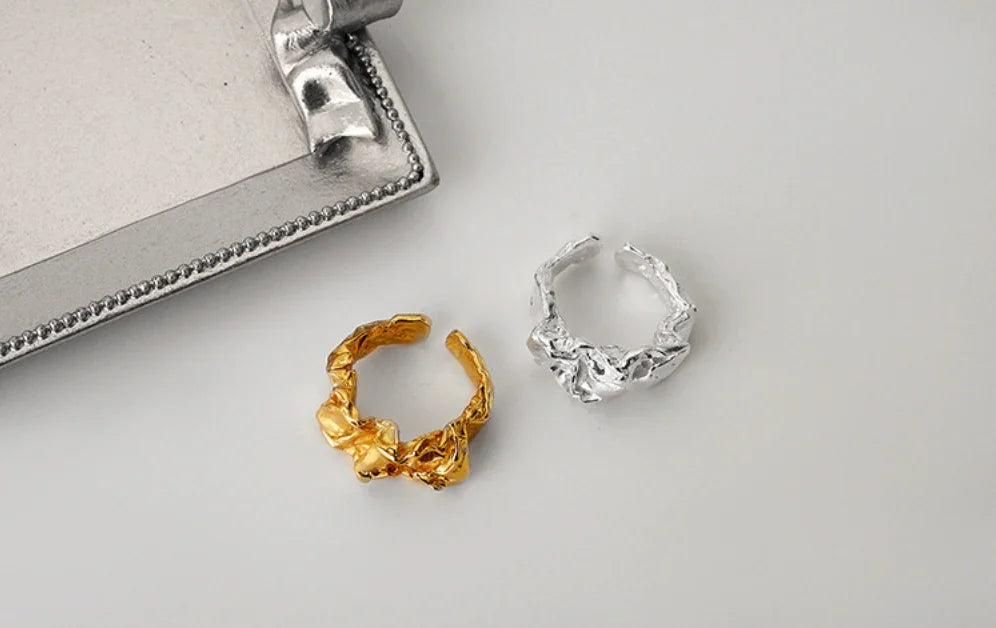 To ringe fra Andcopenhagen Jewelry, én 18 karat guldbelagt og én i sølv, model Arlinda, vises på en lys baggrund.