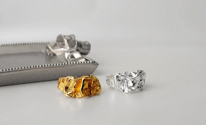 Arlinda ring fra Andcopenhagen i 18 karat guldbelagt og 925 sterlingsølv vist ved siden af et dekorativt fad.