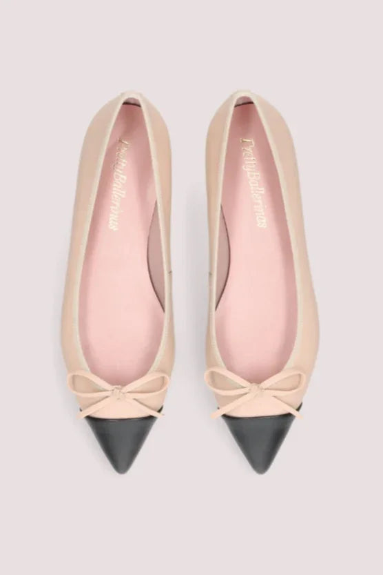 Elegante beige ballerinasko med sort spids tå, dekorativ sløjfe og flad sort sål.