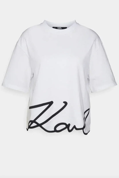 Hvid T-shirt med rund hals og sort, kursiv signatur på kanten.