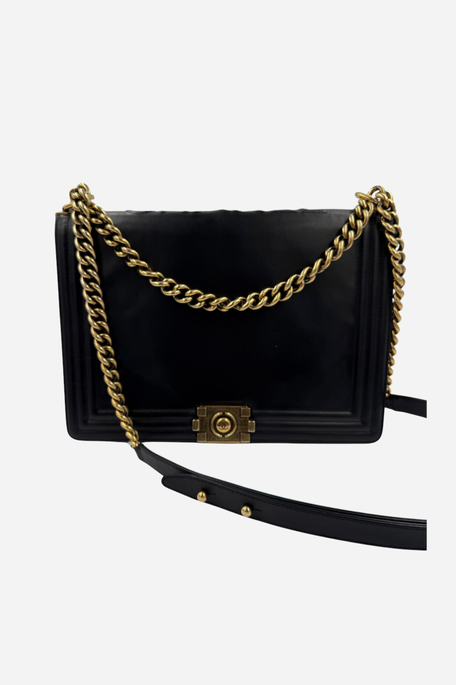 Sort Chanel Boy taske med blank finish, gylden kædestrop og karakteristisk lås foran.
