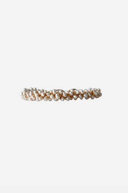 Armbånd med vævede, perlelignende perler i en cirkulær form med knaplukning.