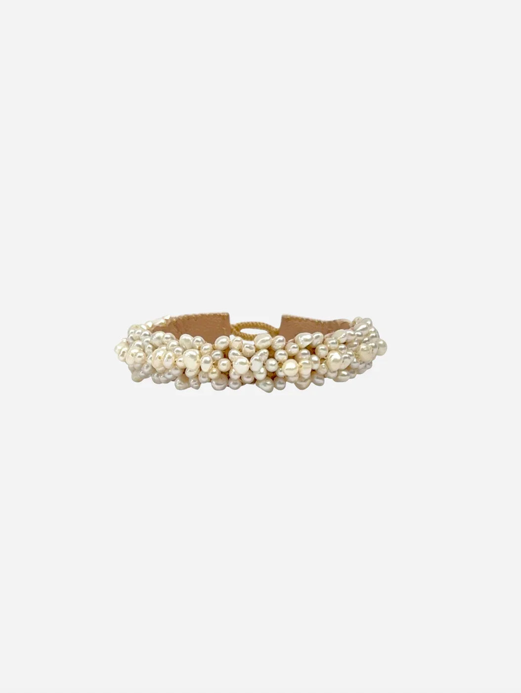 Armbånd med tætpakkede, små, perlelignende perler på lys brun base synlig ved kanterne.