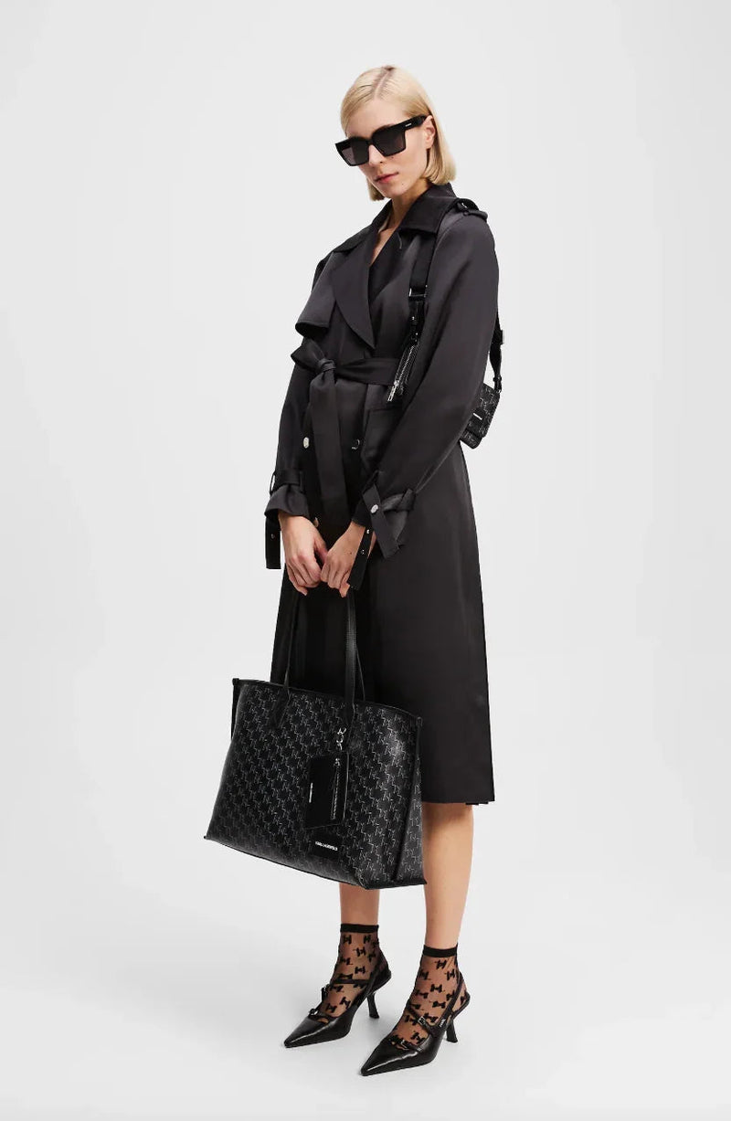 Sort trenchcoat med bred krave, bælte i taljen, og stor taske. Båret med solbriller og mønstrede sokker.