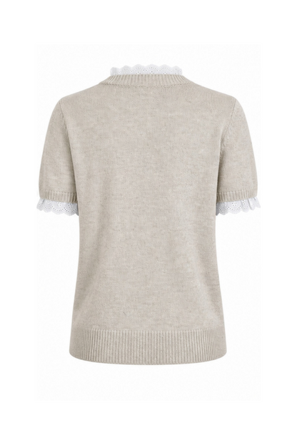 Nirvana er en feminin og stilfuld strikbluse, der kombinerer et klassisk design med romantiske detaljer