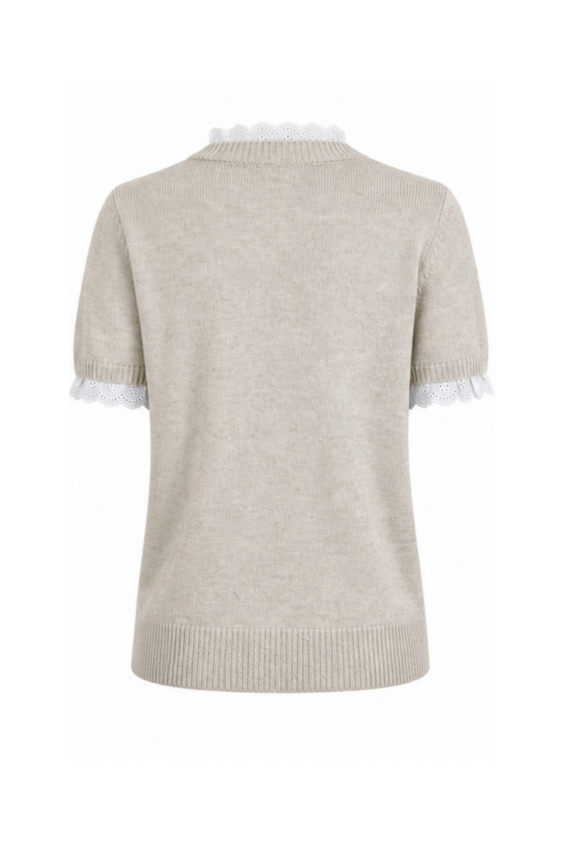 Nirvana er en feminin og stilfuld strikbluse, der kombinerer et klassisk design med romantiske detaljer