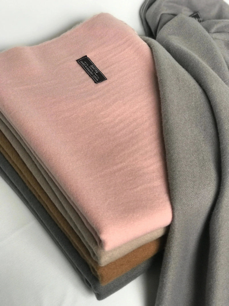 Andcopenhagen Basics cashmeretørklæde i sandfarve, 70% cashmere, model Yana, lagt sammen på hvidt underlag.