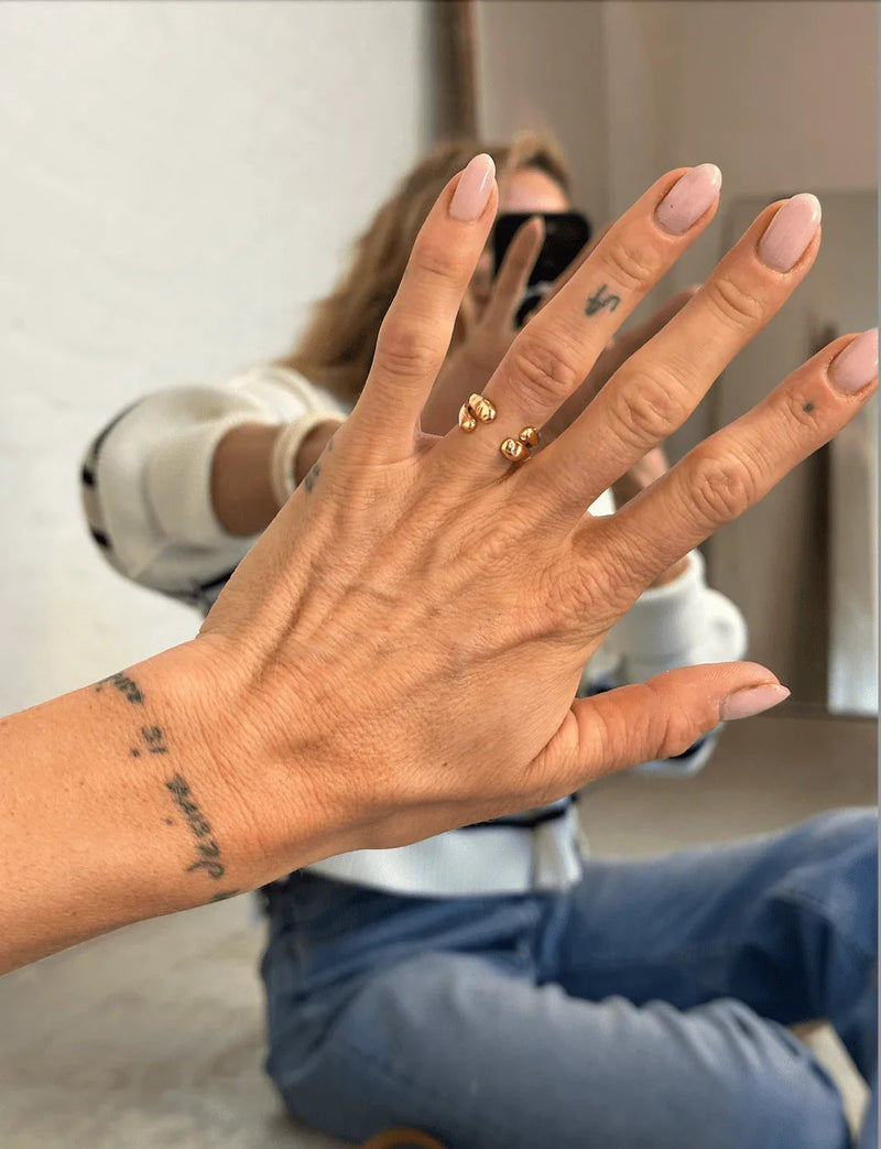 Kvinde viser Lula-ring i 18 karat guldbelagt sterlingsølv fra Andcopenhagen Jewelry på produktside.