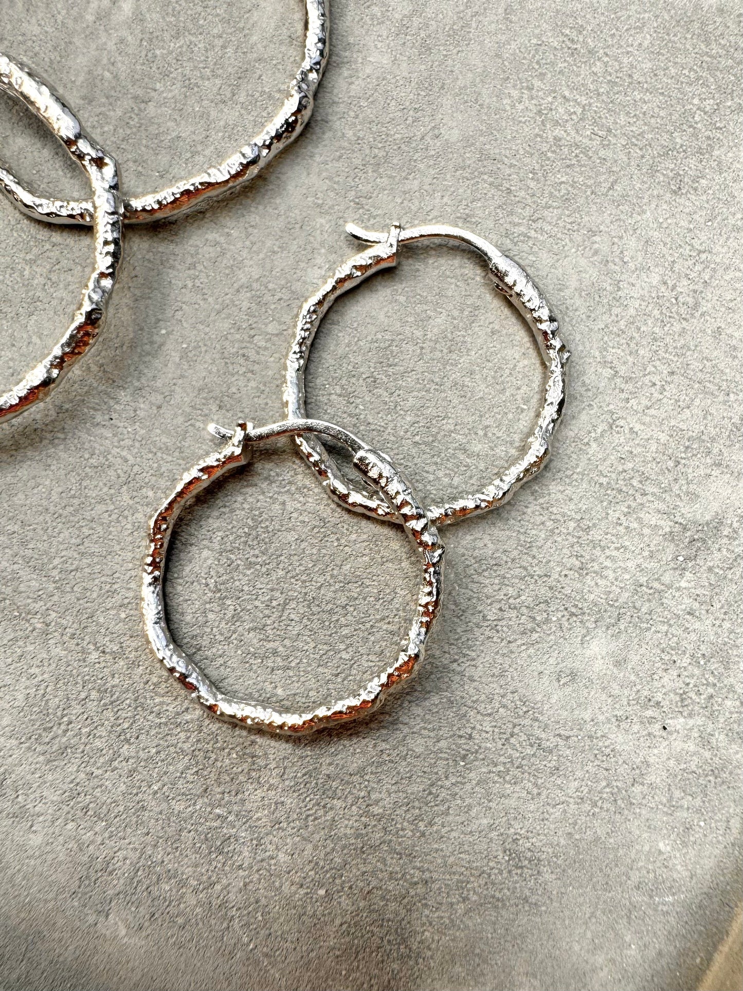 Sølv Sicca small hoops øreringe fra Andcopenhagen Jewelry i hamret 925 sterlingsølv, vist på lys baggrund.