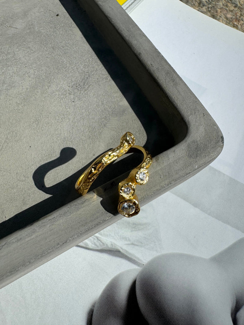 Andcopenhagen Elvira ring i 18 karat guldbelægning med flere klare sten, præsenteret på grå bakke.