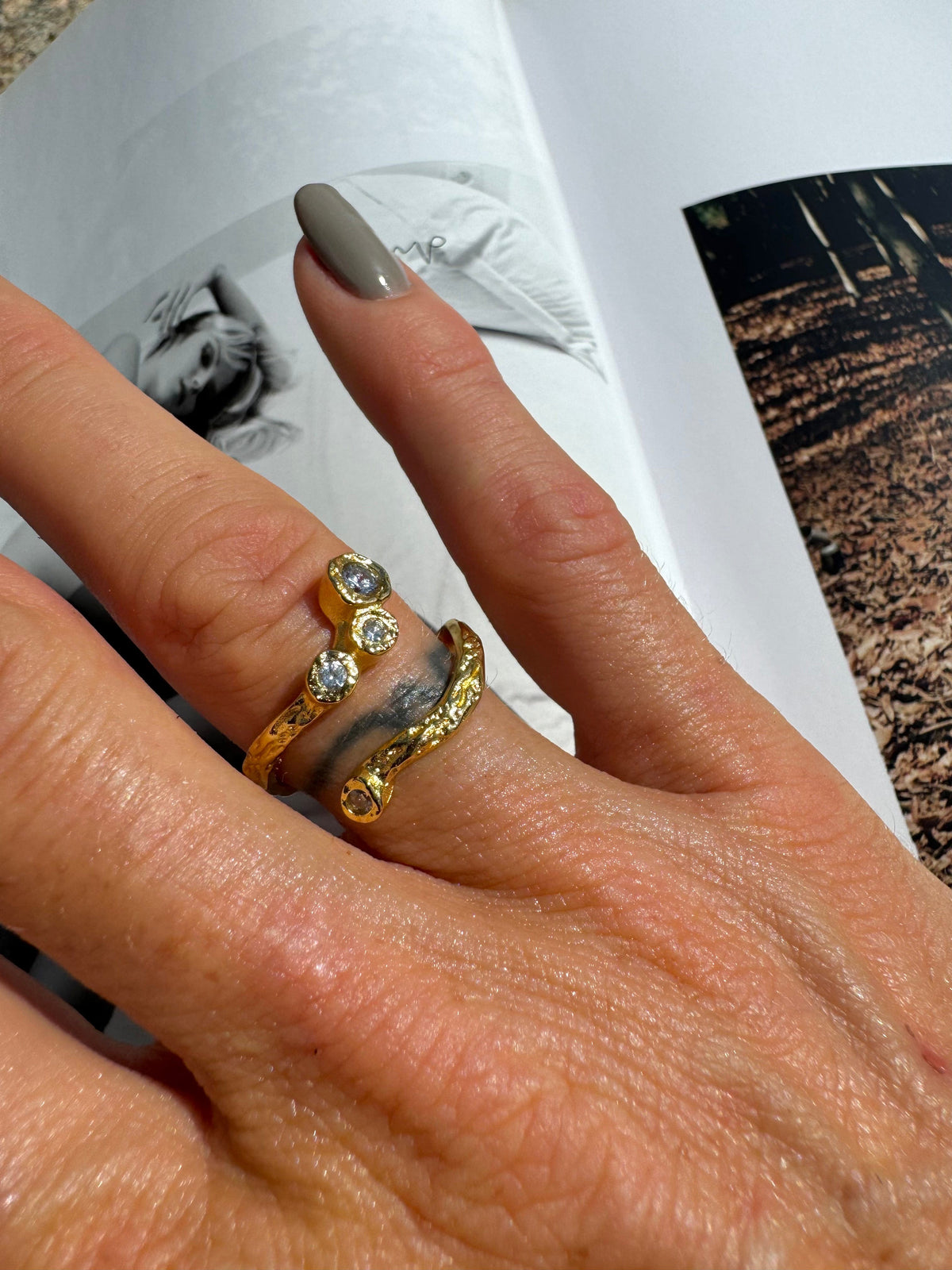 Elvira ring i 18 karat guldbelagt fra Andcopenhagen Jewelry, båret på finger med lysegrå neglelak.